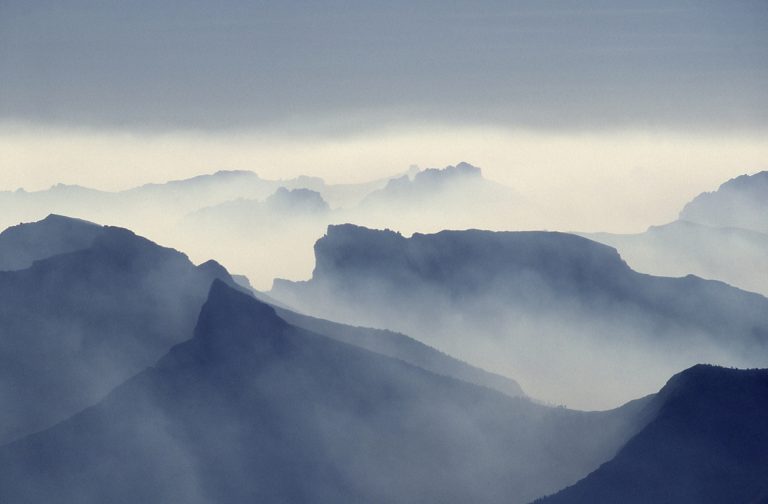 Misty blue mountain ridges fading into low clouds